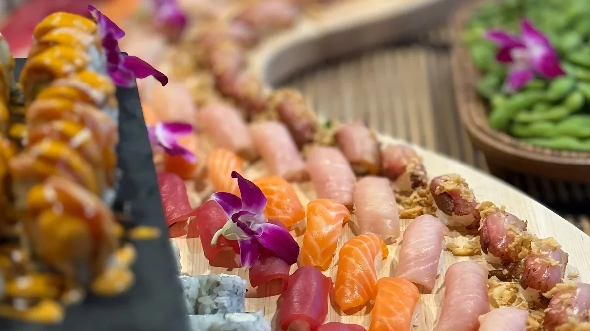 Rows of salmon, tuna and yellowtail nigiri with orchids