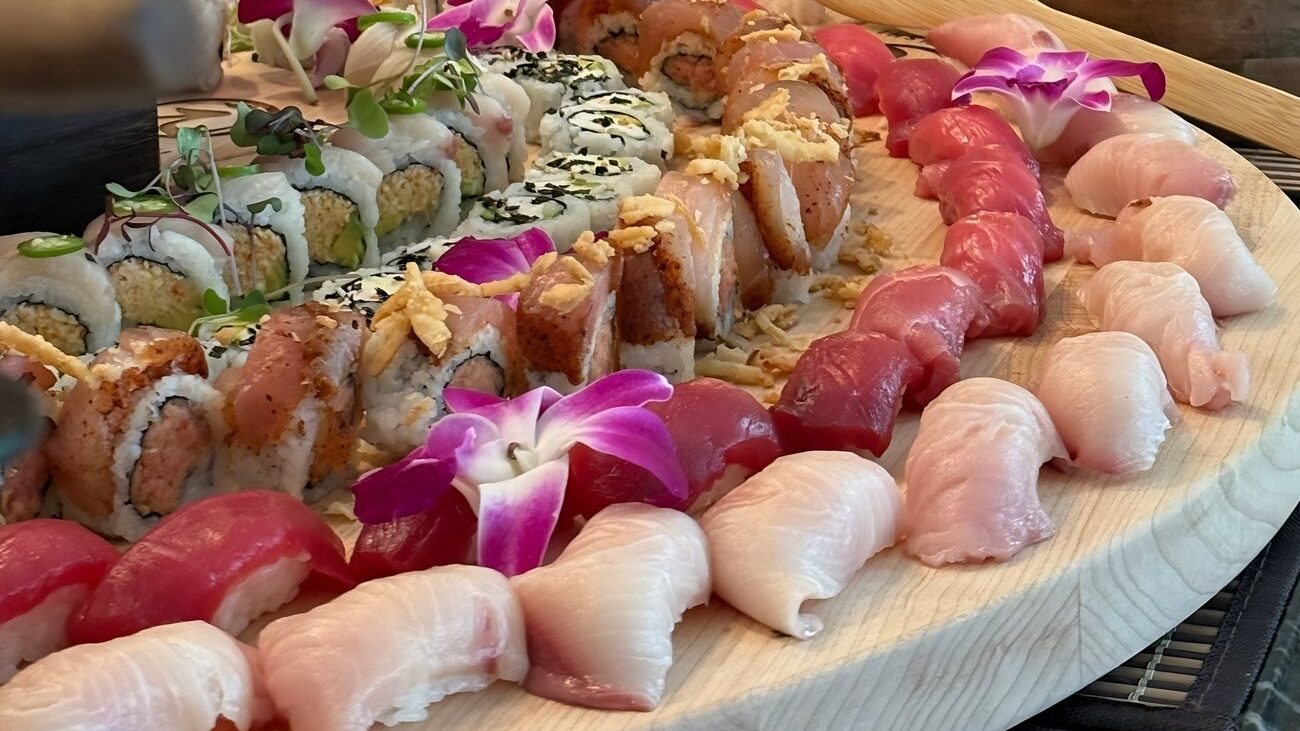 Platter of tuna and yellowtail nigiri and specialty rolls with orchids