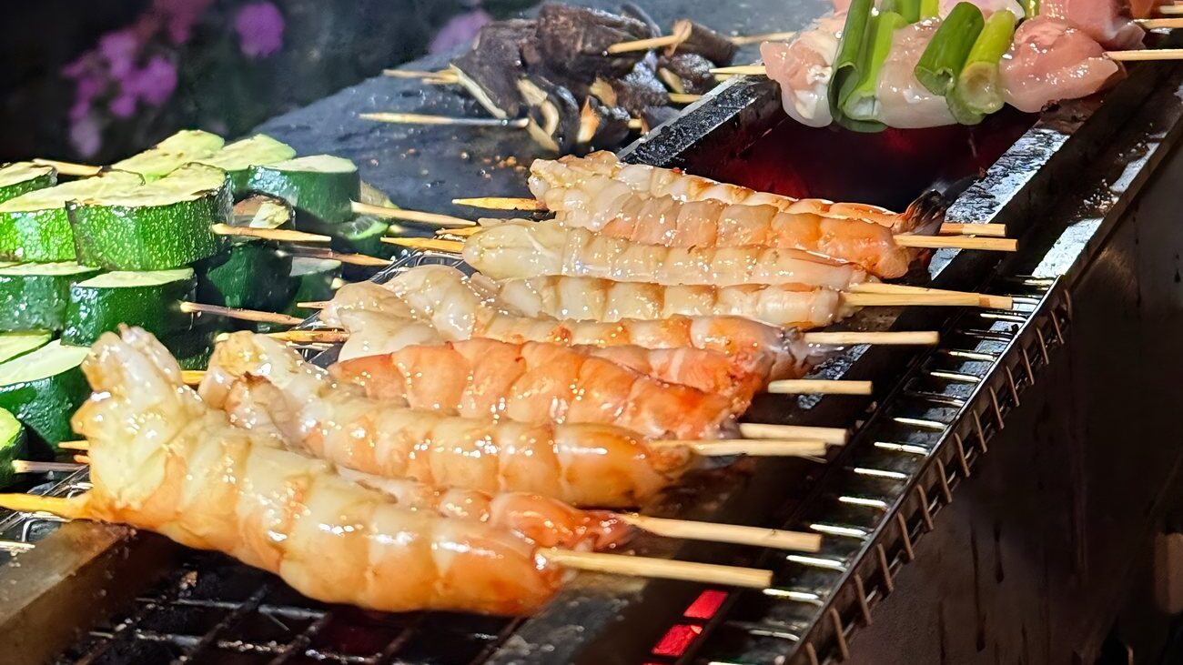 Shrimp, zucchini and chicken yakitori skewers grilling over charcoal