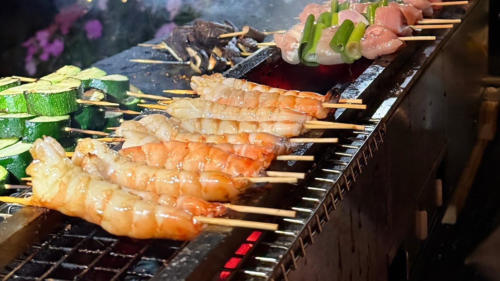 Shrimp, zucchini and chicken yakitori skewers grilling over charcoal