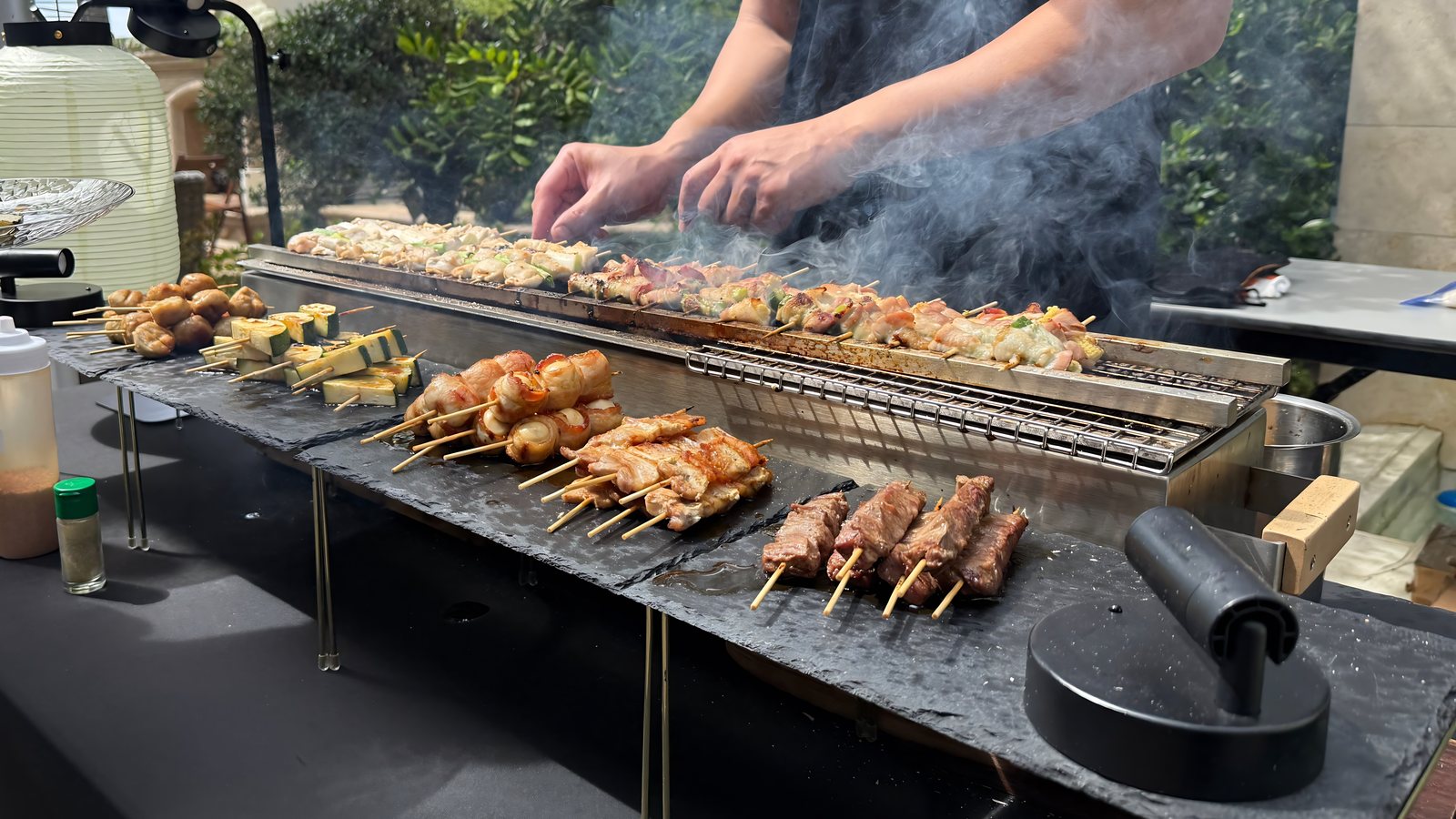 Chef grilling a spread of yakitori skewers at an outdoor event